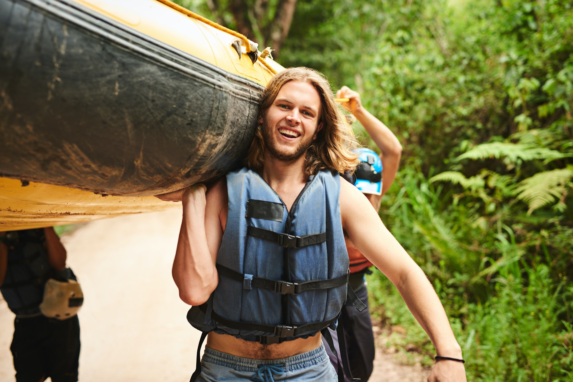 Cropped portrait of a handsome young man and his friends carrying their raft towards the water