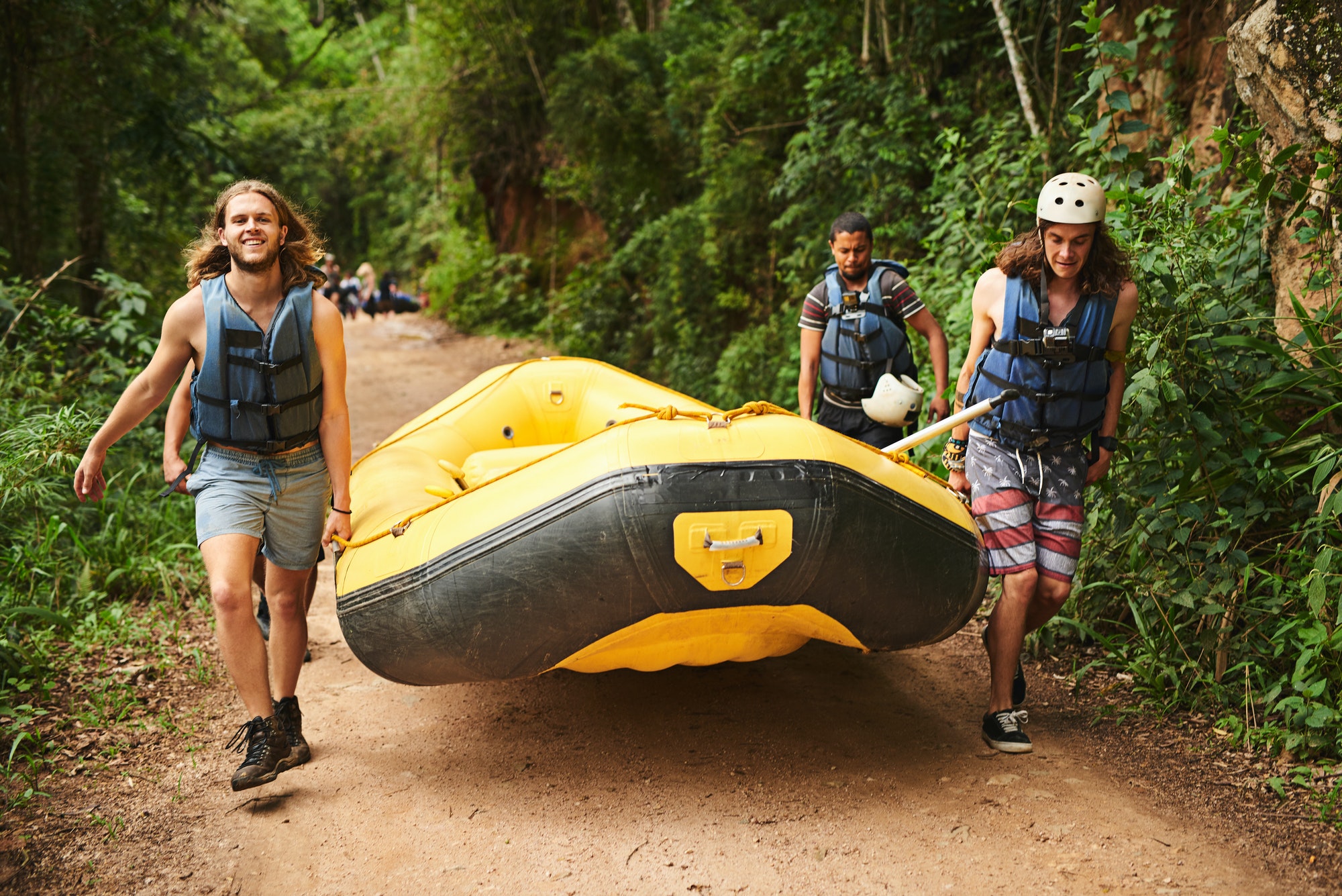 Full length portrait of a handsome young man and his friends carrying their raft towards the water