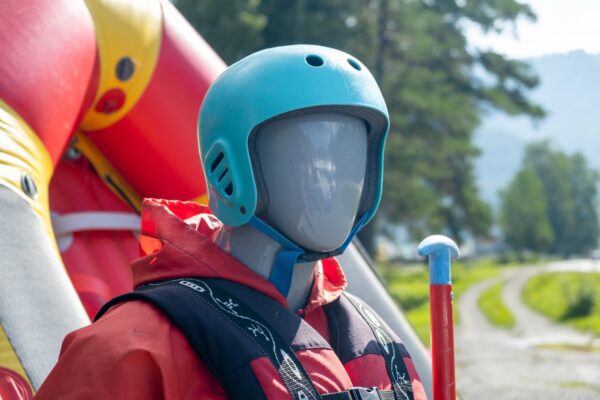 A mannequin in a red life jacket next to an inflatable boat