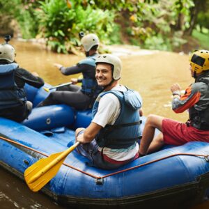 High angle portrait of a handsome young man and his friends sitting in their white water raft